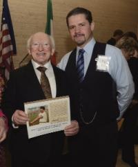 New York, May 2012—President Michael D. Higgins is presented with an enlarged replica of a cigarette card of triple Olympic hammer champion John J. Flanagan by Ian McGowan, director of the Winged Fist Organisation. (James Higgins)