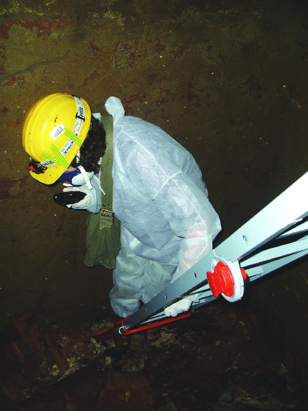 Pl. 7: The author standing above the coffin debris and scattered burials in the vault below hatch H. (L. Bartlam)